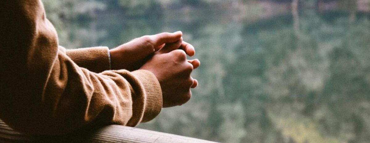 person hold their hands together as they look out into the distance thinking about recovery from addiction