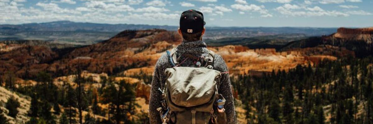 a man stands at the top of a mountain representing mental health treatment for military