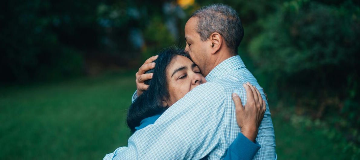 husband and wife embrace each other as the husband struggles with addiction