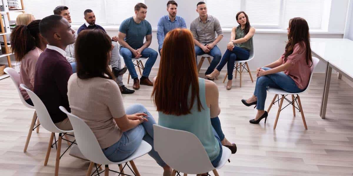 A supportive group therapy session where individuals openly share their thoughts, sparking the consideration: Do I need rehab?