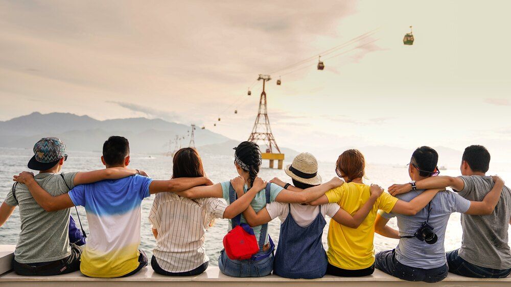 Group of young adults sitting by each other looking at the sky