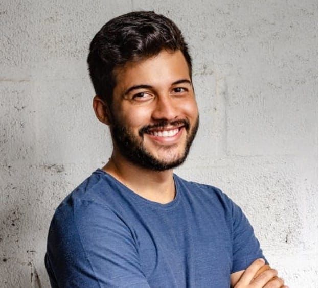 Man in blue shirt, arms crossed and smiling