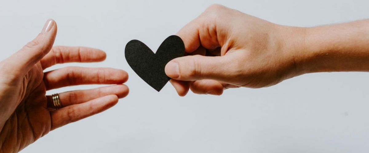 Two people passing a piece of paper shaped like a heart