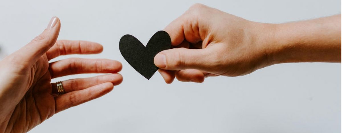 Two people passing a piece of paper shaped like a heart