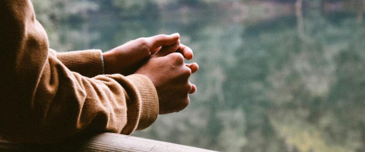 person hold their hands together as they look out into the distance thinking about recovery from addiction