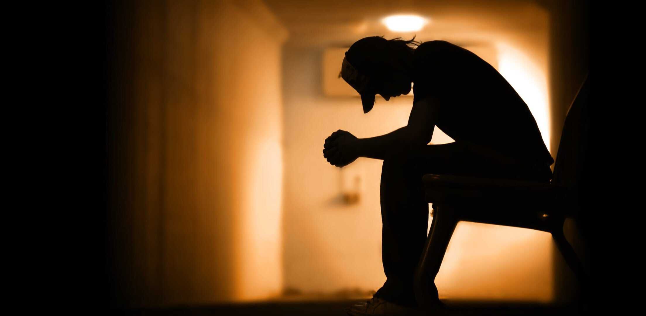 A man sitting alone in a dark hallway struggling with drug addiction