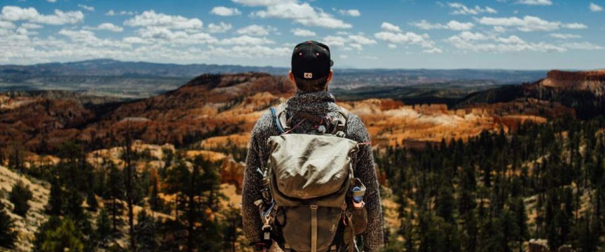 a man stands at the top of a mountain representing mental health treatment for military