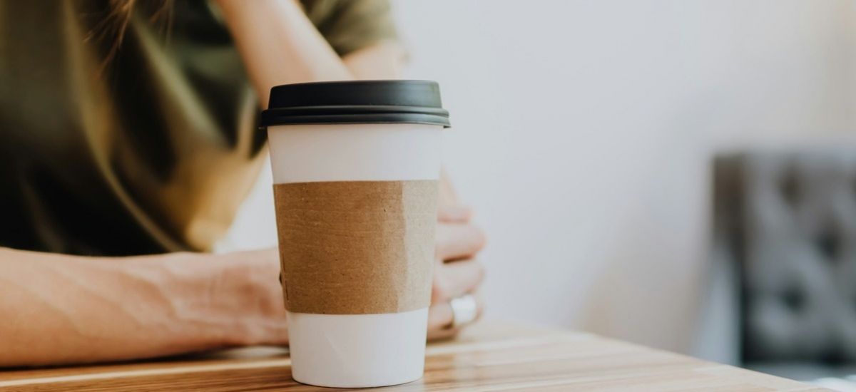 girl sits at a desk with a cup of coffee to go representing substance abuse treatment