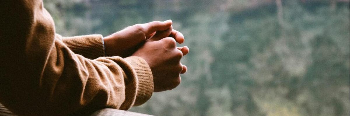 person hold their hands together as they look out into the distance thinking about recovery from addiction