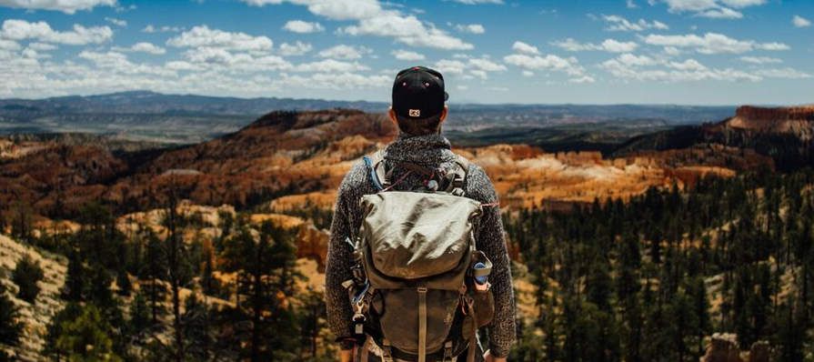 a man stands at the top of a mountain representing mental health treatment for military