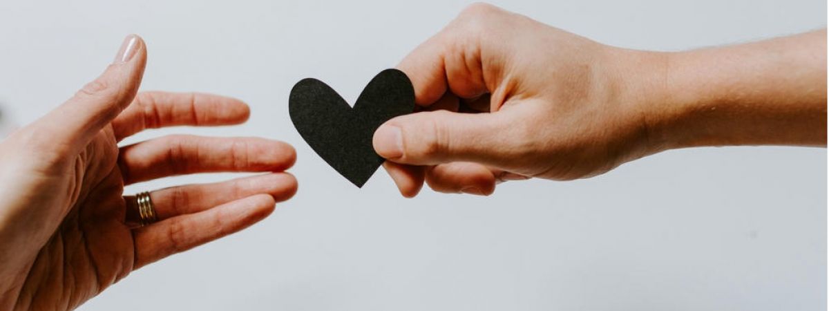 Two people passing a piece of paper shaped like a heart