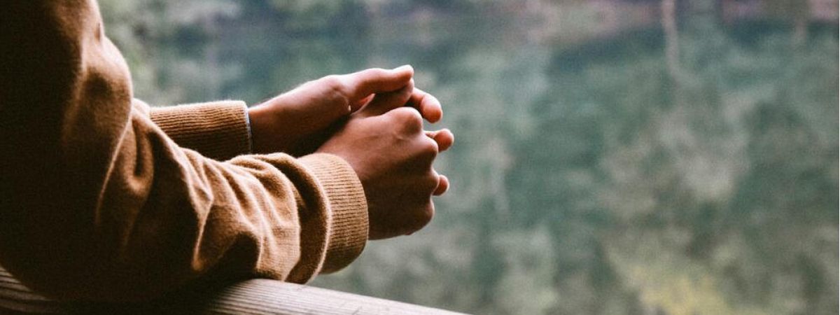 person hold their hands together as they look out into the distance thinking about recovery from addiction