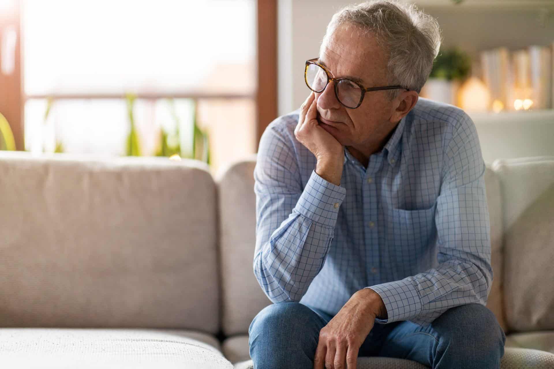 a man with both alcoholism and depression sits on his couch